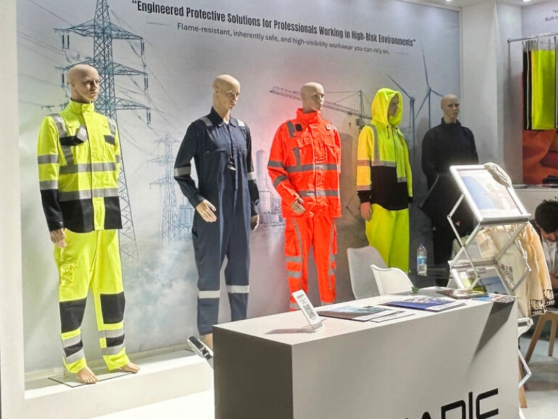 Close view of Nomadic FR and IFR workwear including high-visibility coveralls displayed at HSE safety exhibition booth